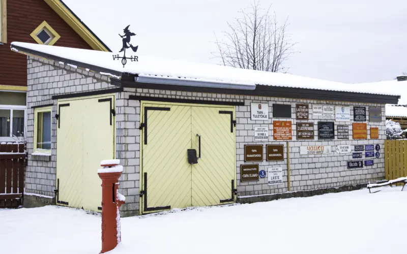 Tapa Muuseumi õuel asuv kuur talvel, seinal vanad sildid ja ees punane tuletõrjehüdrant